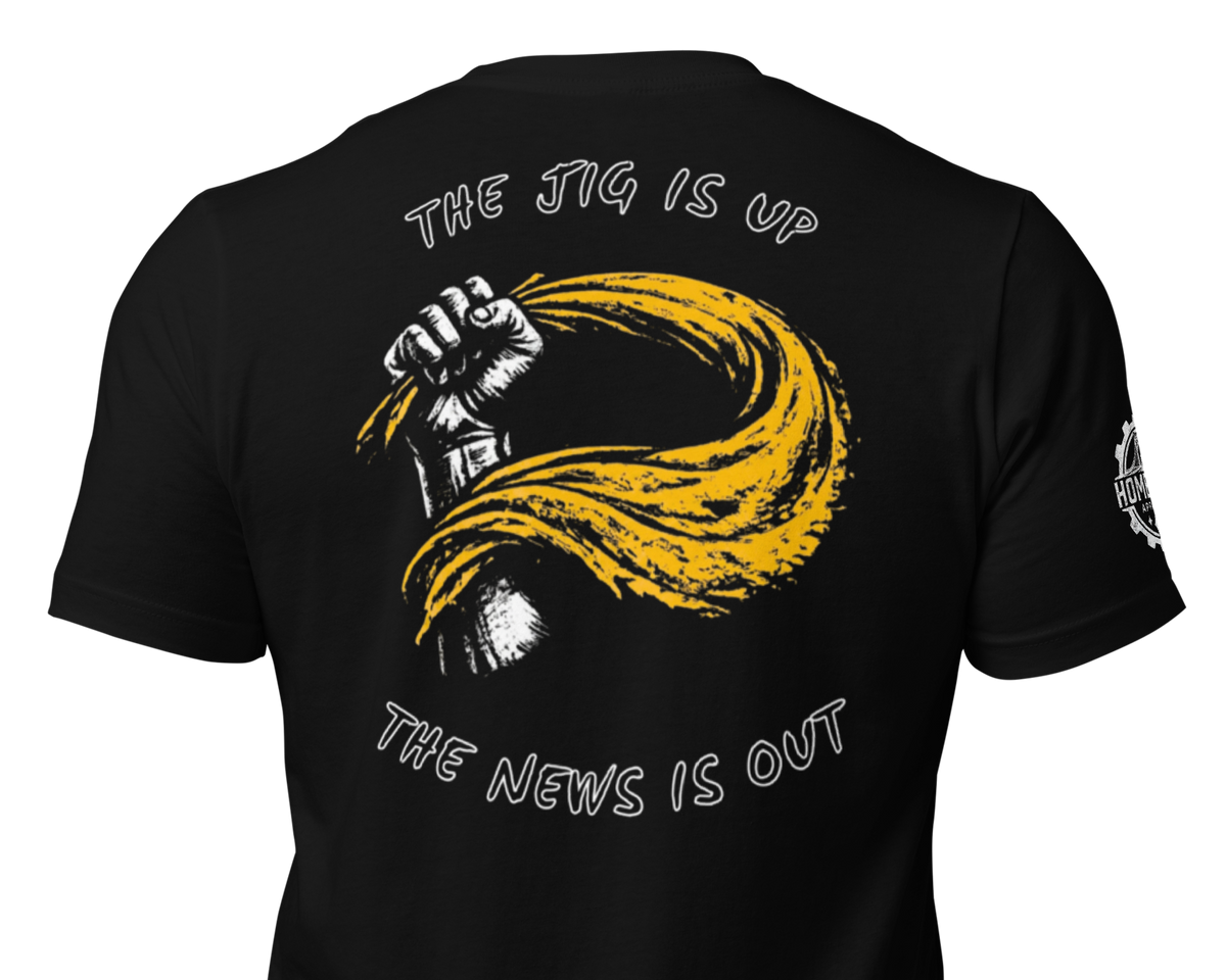 Black short-sleeve t-shirt shown from the back, featuring a large graphic print of a raised fist in white and yellow with the text 'THE JIG IS UP' above and 'THE NEWS IS OUT' below.